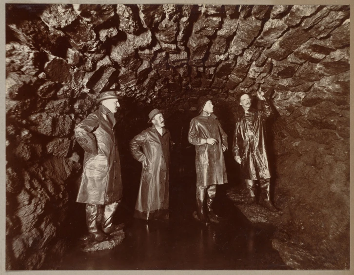 three men are standing in front of a cave