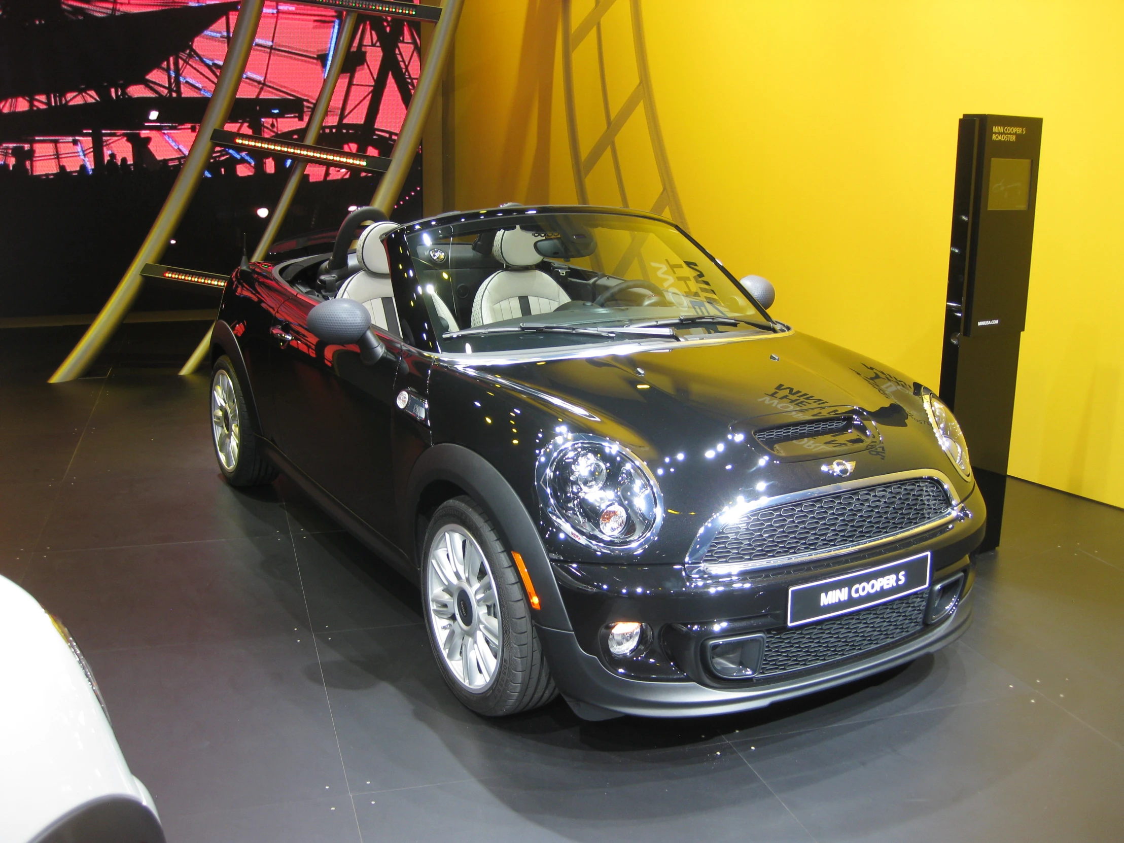 a shiny black convertible car parked next to a ladder