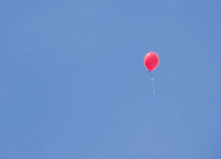 a red balloon floating high in the sky