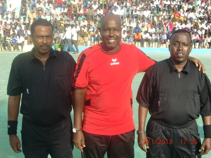 three men standing next to each other in front of a large crowd