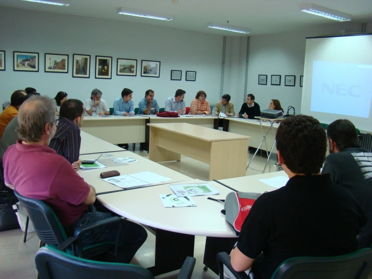 people in a classroom watching a presentation with a projector screen behind them