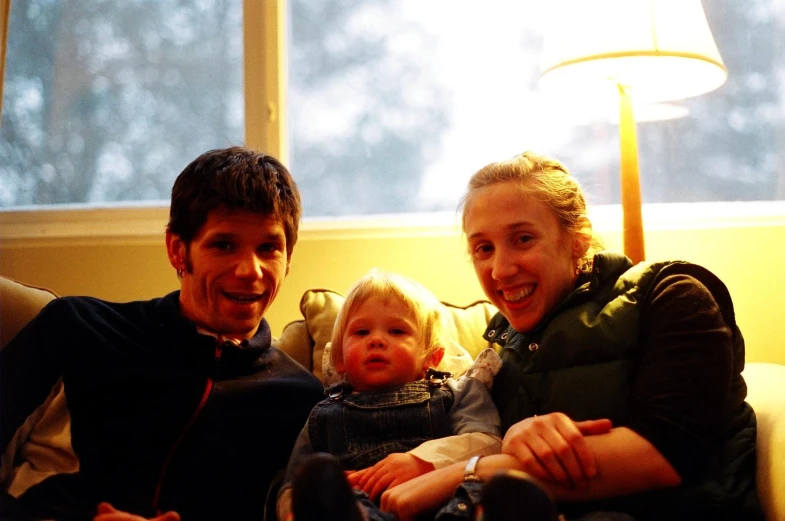 a couple and their child on the couch in front of a lamp