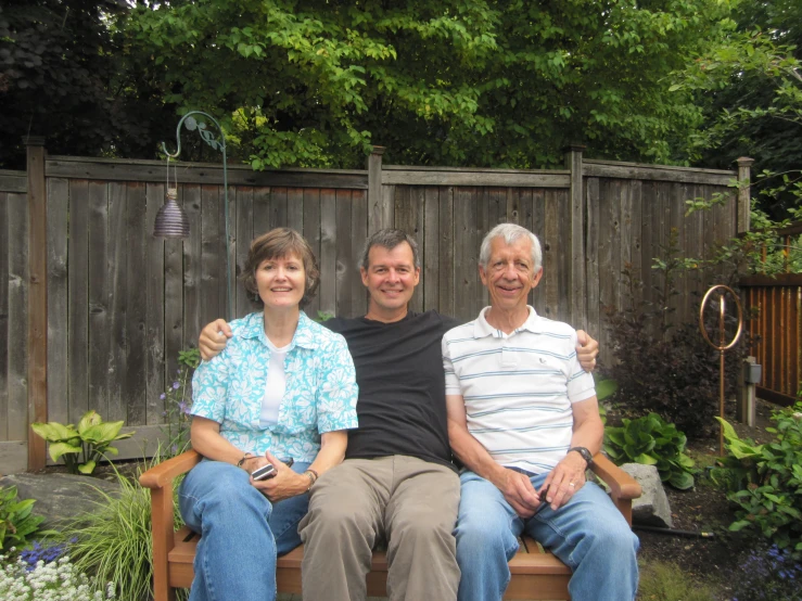 two men and a woman sitting next to each other on a bench