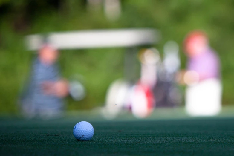 a golf ball sitting on a field near another person