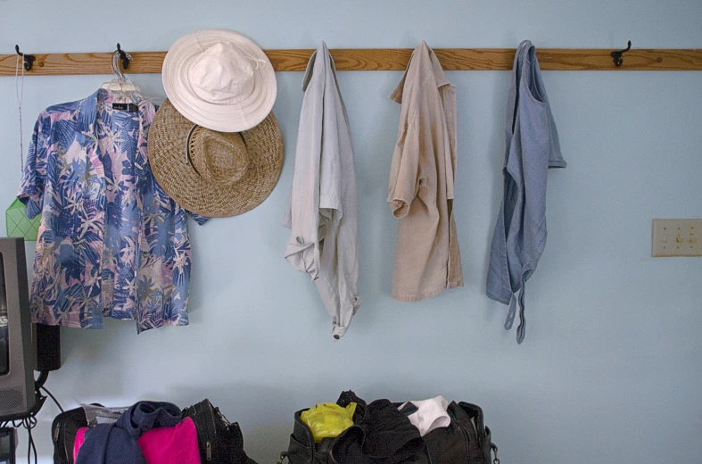 a few jackets, hats and a bag hanging from a wall