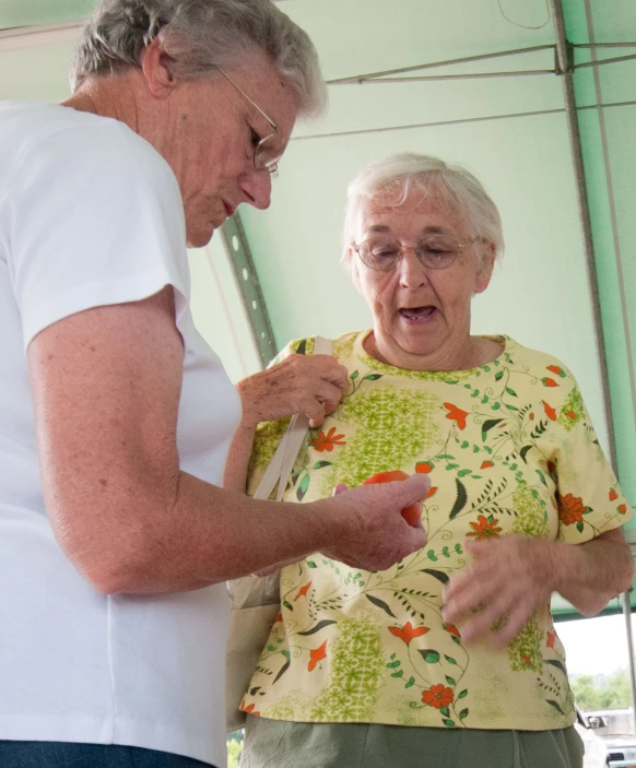 an older woman is helping a younger lady cut soing