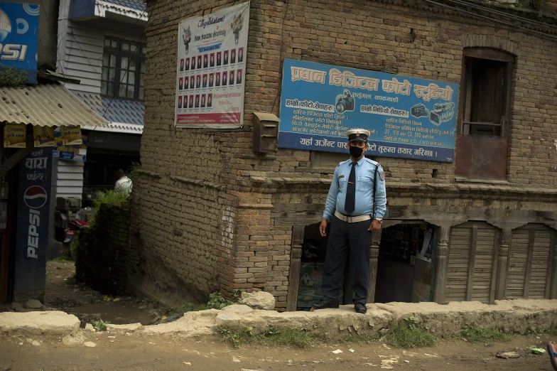 a man wearing a hat standing in front of a brick building