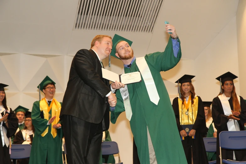 a man shaking another man's hand in graduation attire
