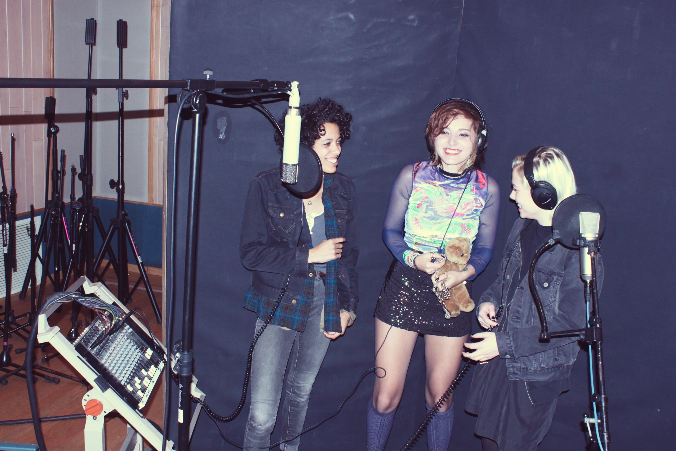 there are three girls posing together in front of microphones