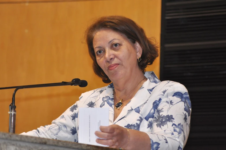 a woman wearing a floral shirt reading a piece of paper