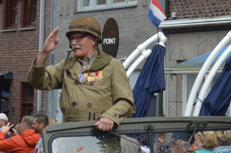 an older gentleman wearing a hat and uniform waving at someone
