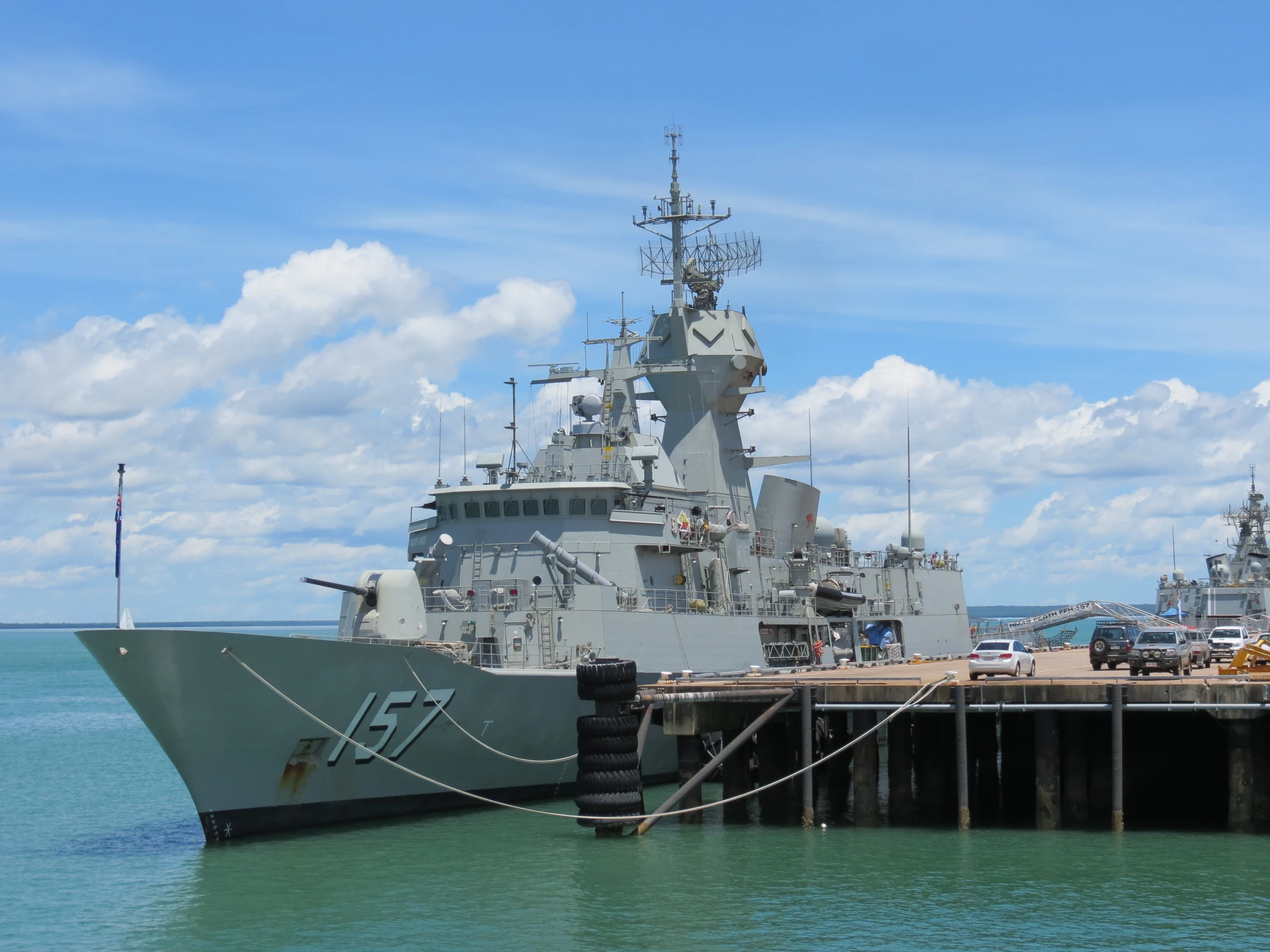 a large gray ship is docked near a pier