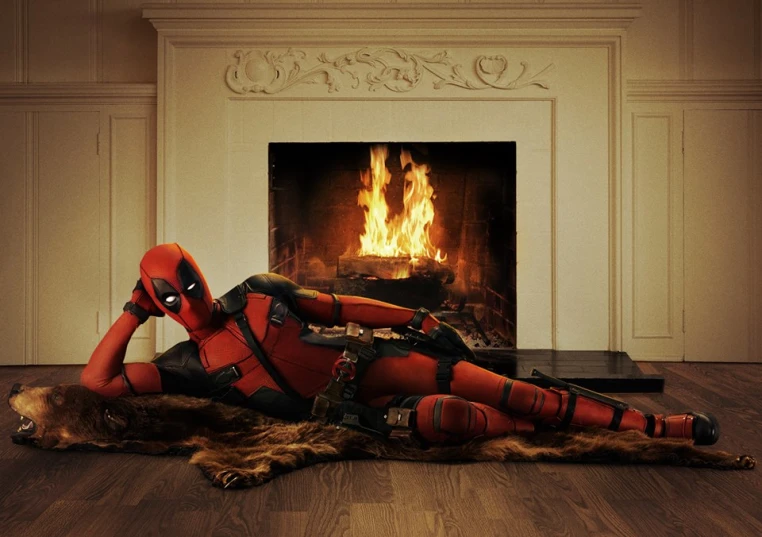 a woman dressed in deadpool is laying on the ground next to a fire