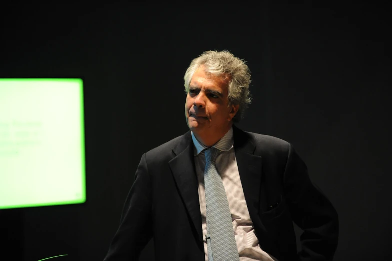 a man in a business suit standing next to a black background