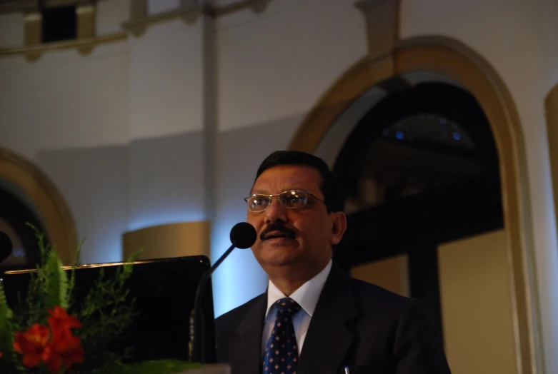 a person with glasses talking at a podium