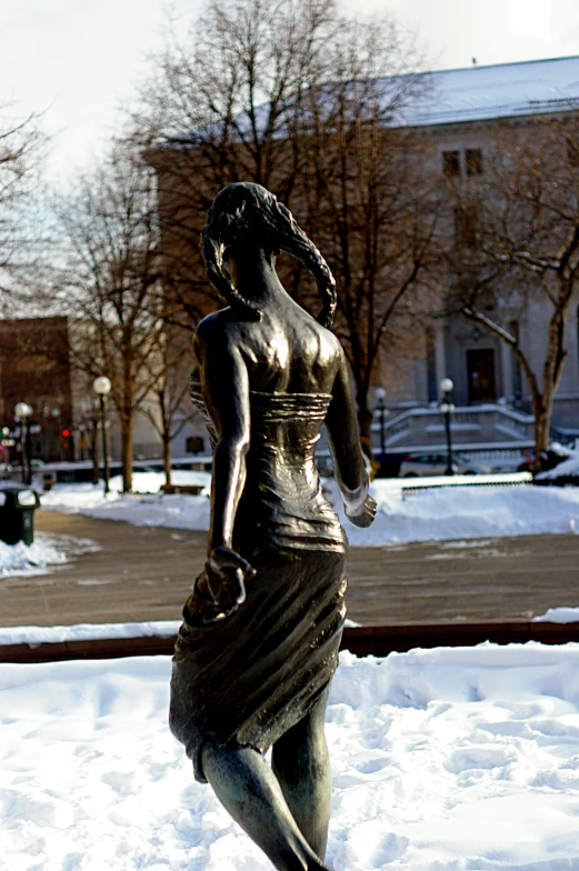 a statue is sitting in the snow in a park