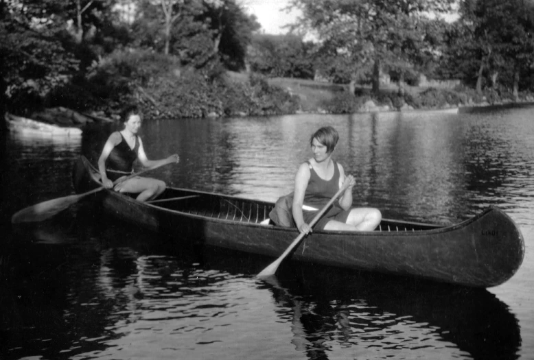 two women are sitting on a canoe on the water