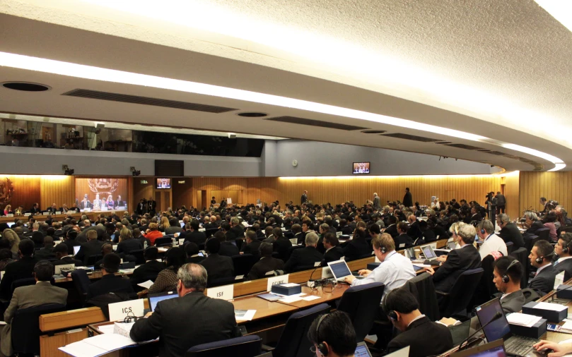 large group of people in a meeting room with electronic equipment