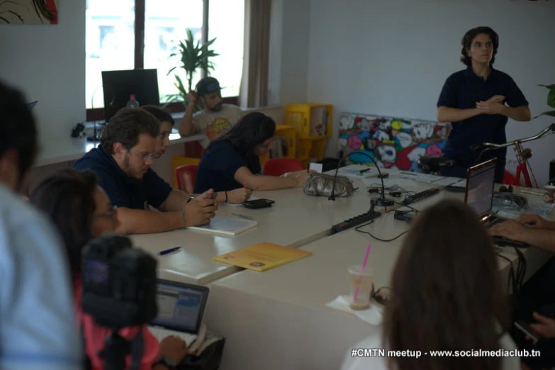 a group of people sitting around a table with laptops