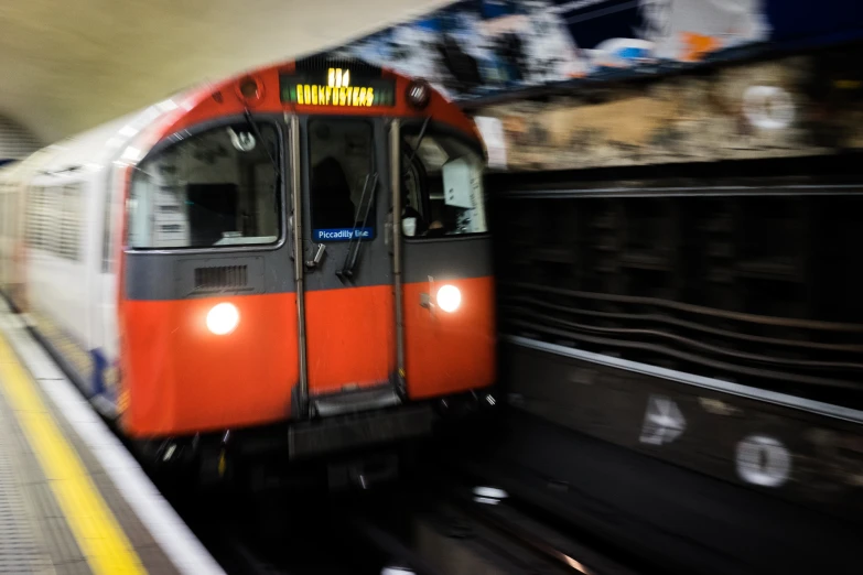 a red train moving down the tracks in the underground