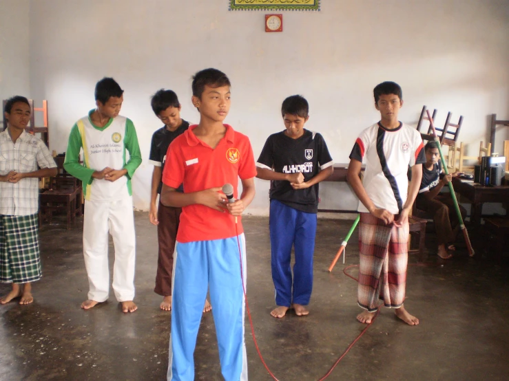 a group of s in a room with one boy in red shirt and two boys wearing blue pants standing next to each other