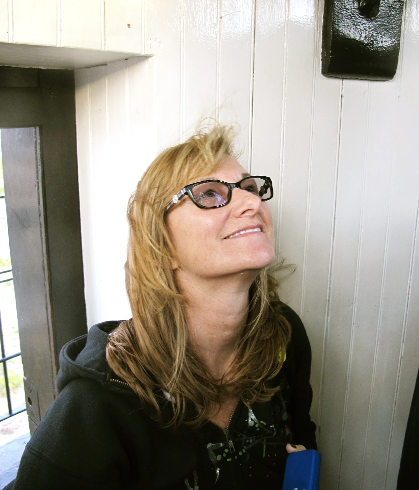 a beautiful blonde wearing glasses leaning against the wall