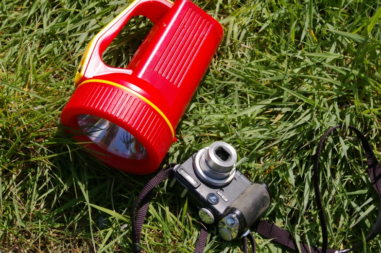 an old camera is laying on grass with a red object nearby