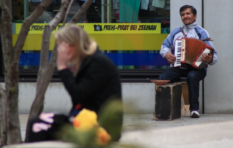 a woman and a man sit on benches while playing the accordions