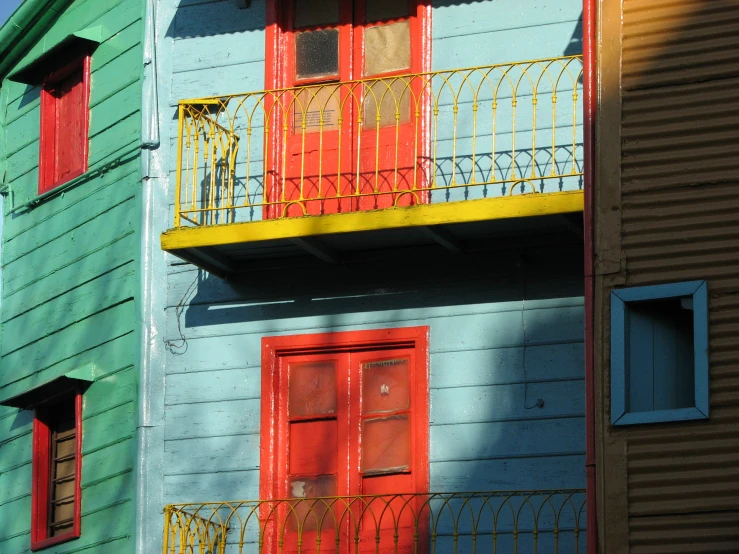 the building has four windows with red doors and a balcony