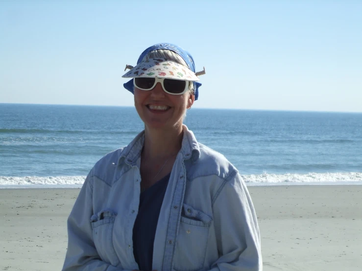 there is a woman standing on the beach wearing shades