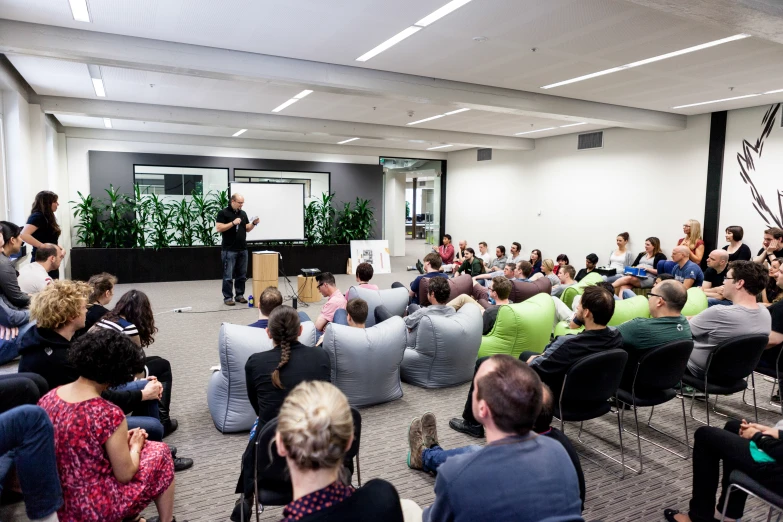 people sitting in chairs watching an adult speak at a podium