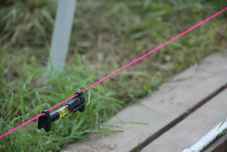 a fishing pole attached to the ground with a line and two other items in front of it