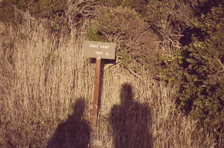 a sign is in the grass on top of a hill