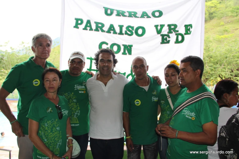 a group of people with green shirts on posing for a picture