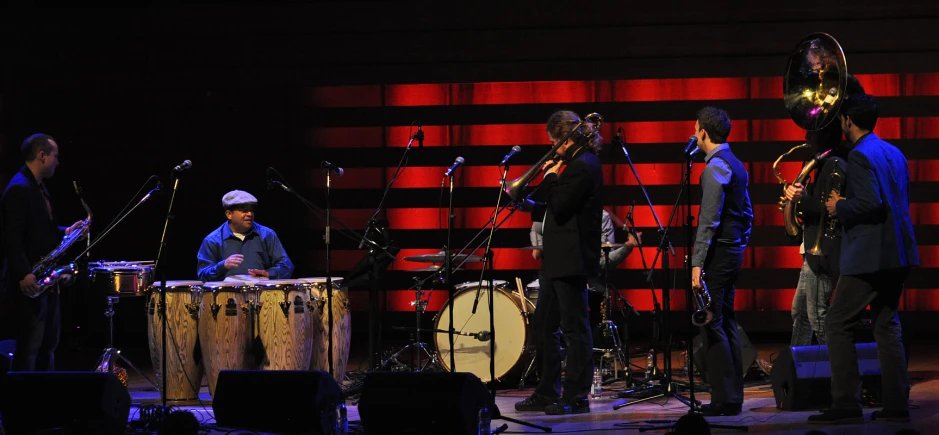 bandleaders perform on stage with instruments and a drum