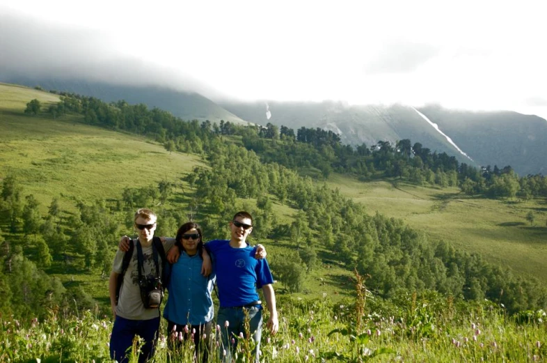 three people standing on a grassy hill side