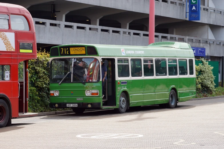 green and red bus sitting beside each other on street