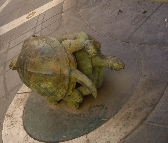 a statue depicting a turtle riding another turtle with its head back