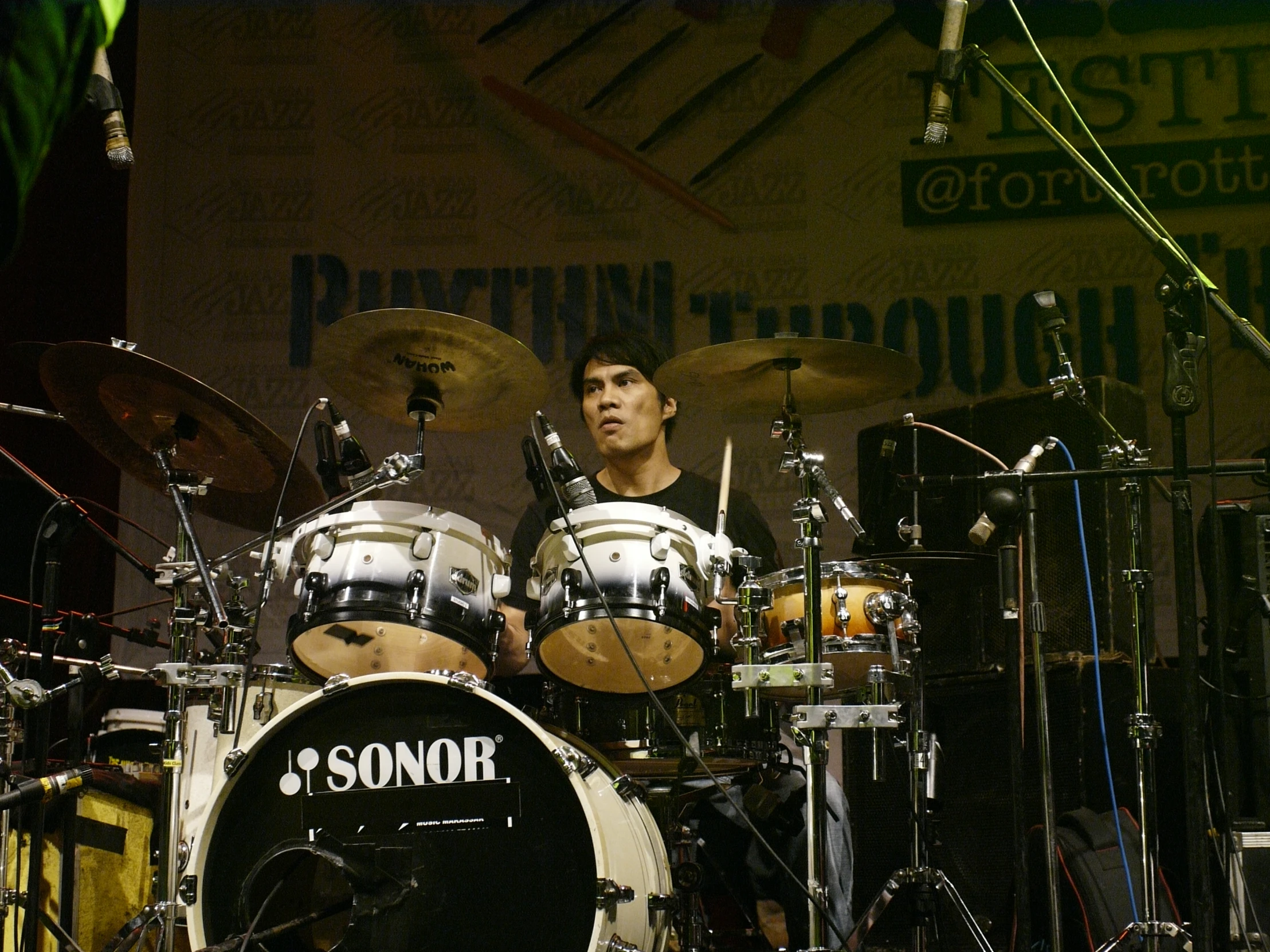drummer playing on drums at a concert in front of microphones