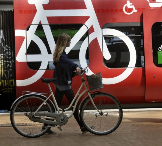 a woman walking her bike by a train