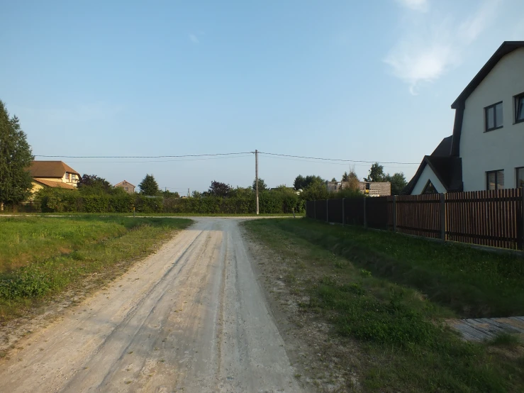 a dirt road leading up a small field and houses