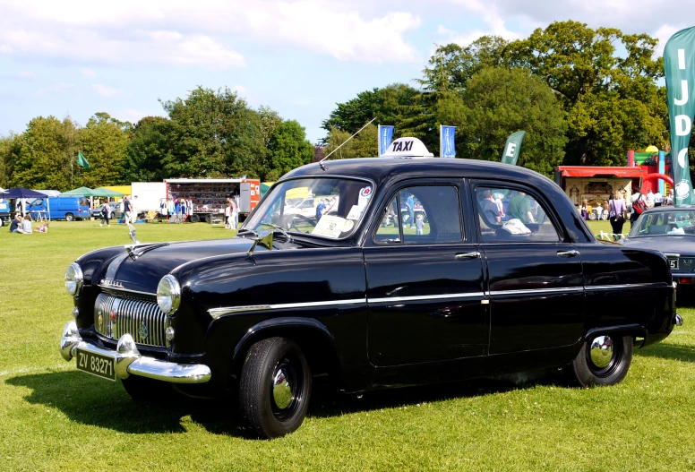 a black classic car on display on the grass