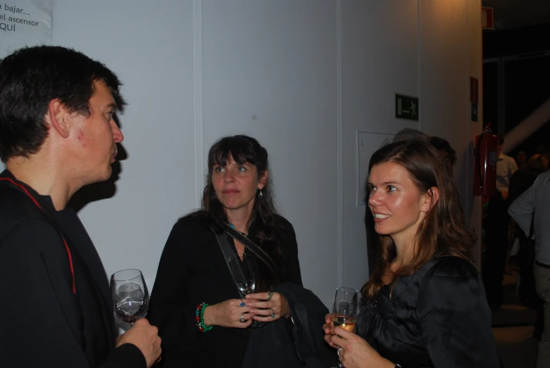 three people standing next to each other with wine glasses