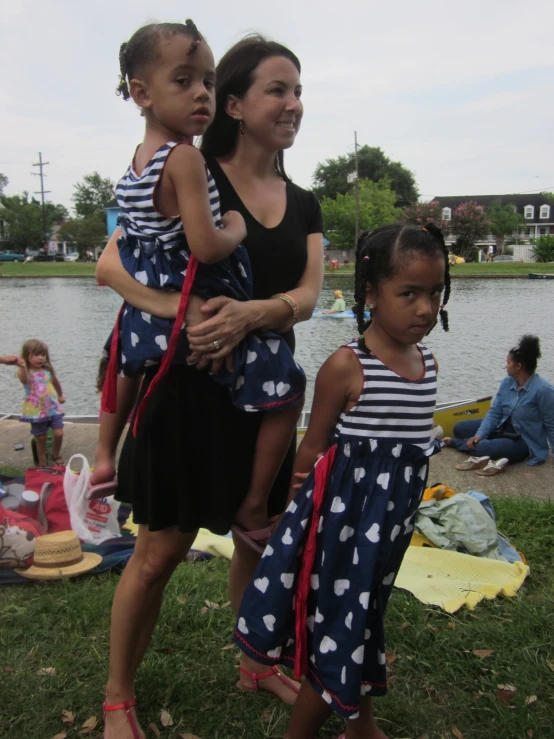 a woman and two children standing by a body of water