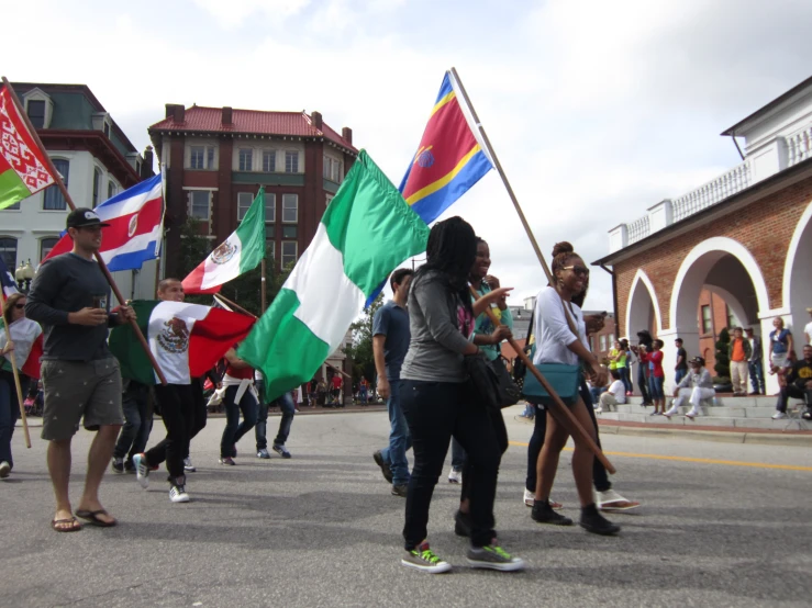 a group of people walk down the street carrying many different flags