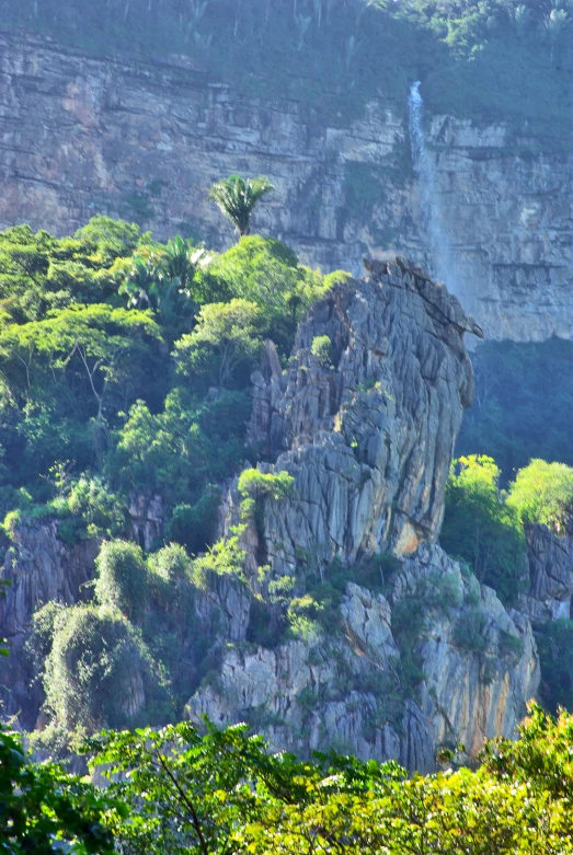 a cliff side with many large rock formations and trees around it