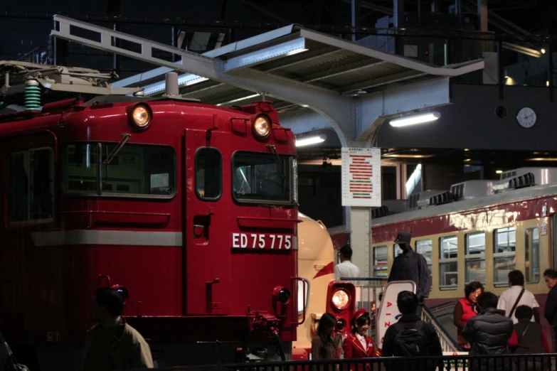 people standing near an old style train in the station