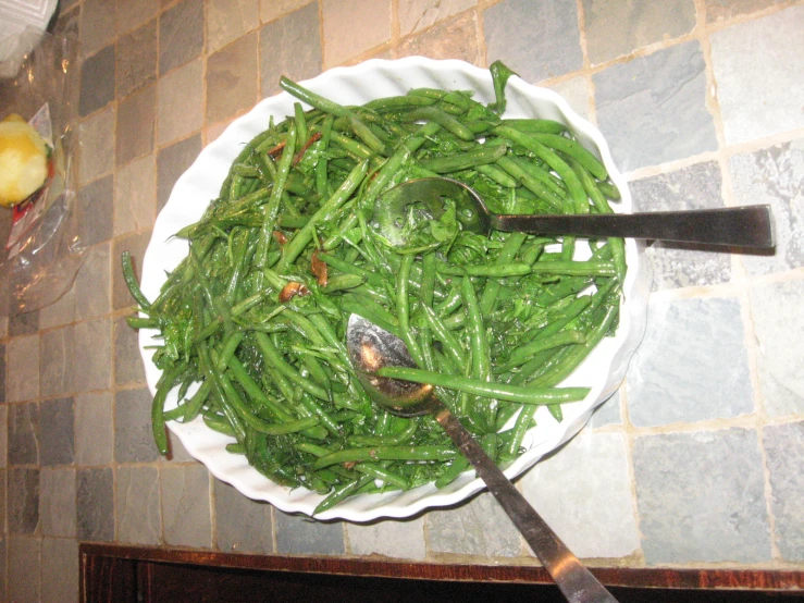 a plate with green beans and a knife sitting on a table