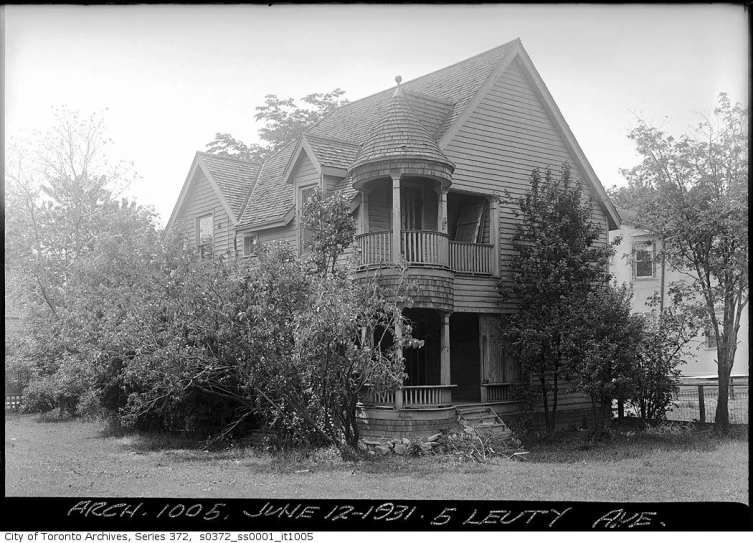 a old house sits near a tree in a wooded area