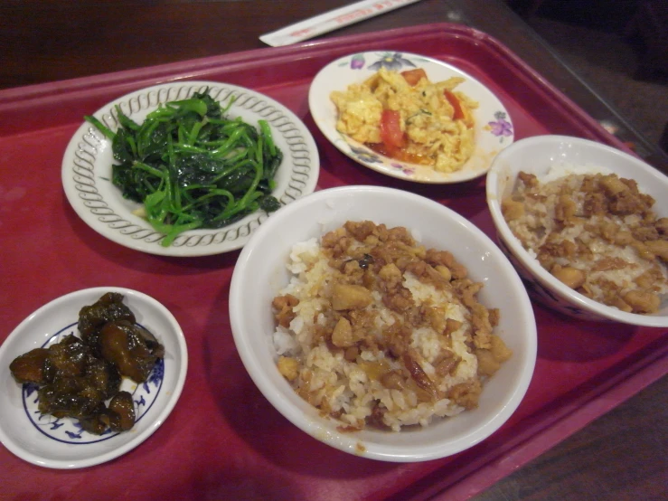 a red tray topped with four plates and food